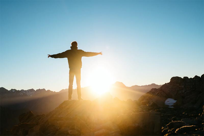 A person standing on a mountain ridge at sunrise
